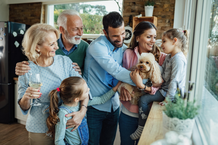 Multigenerational family gathered around a small dog in a kitchen