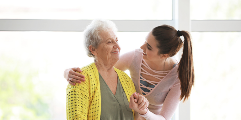 Young woman holding hands with an older woman and smiling at her