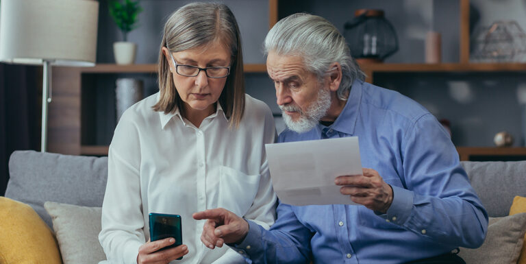 Man and woman reviewing a document and phone together on a couch
