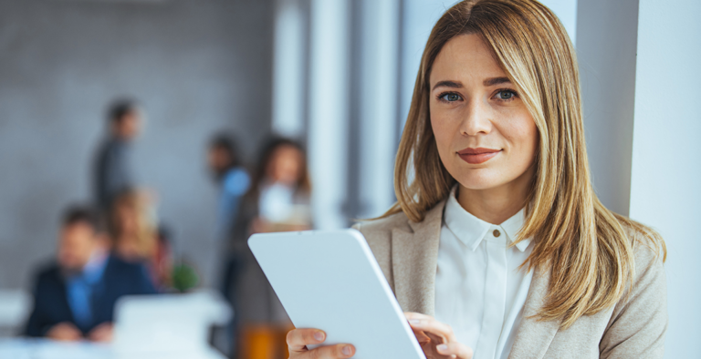 Woman holding a tablet in an office with people in the background
