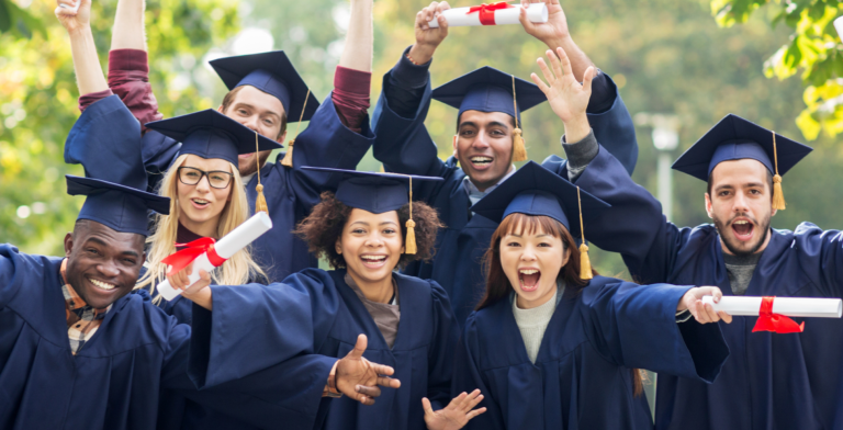 Group of graduates in caps and gowns cheering and holding diplomas
