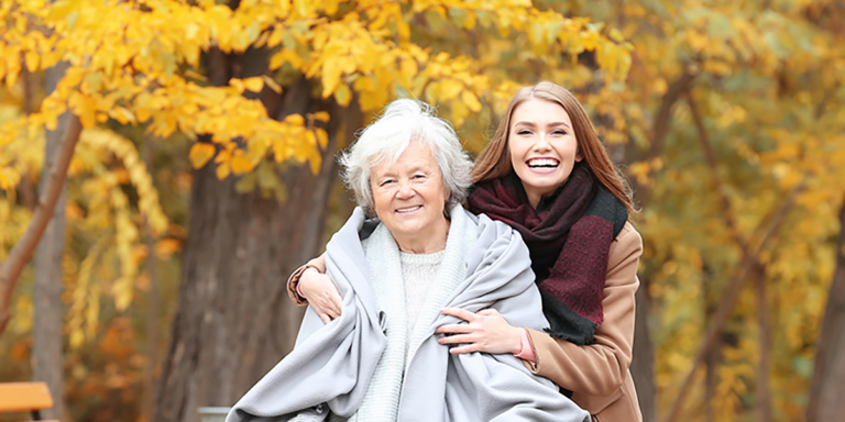 Young woman with her arms around an older woman in a park