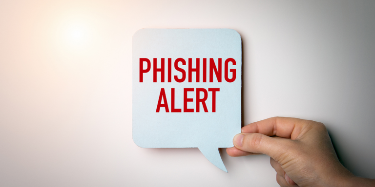 Hand holding a speech bubble sign with text: PHISHING ALERT