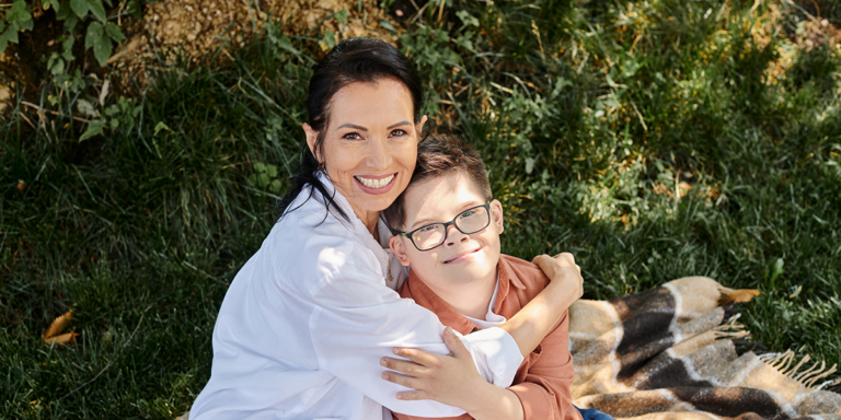 Woman and a young boy embracing outdoors on a blanket